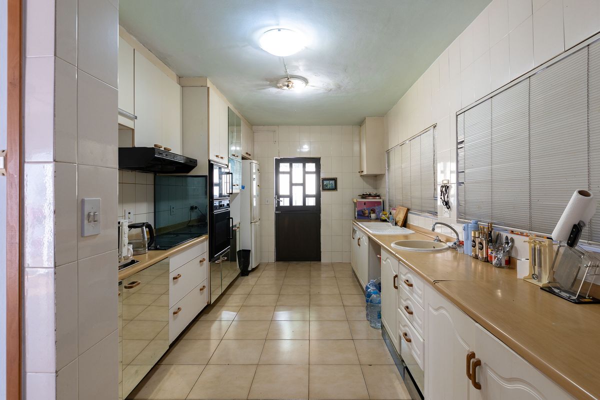 A functional galley-style kitchen featuring built-in cabinetry, double sink, and integrated oven, offering a practical layout with potential for modern cosmetic updates.