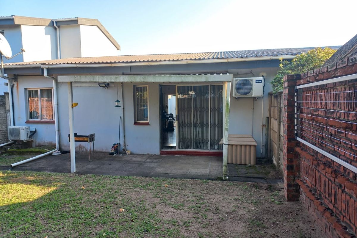 Rear view of the apartment featuring a covered patio area, sliding glass doors, and an outdoor air conditioning unit.