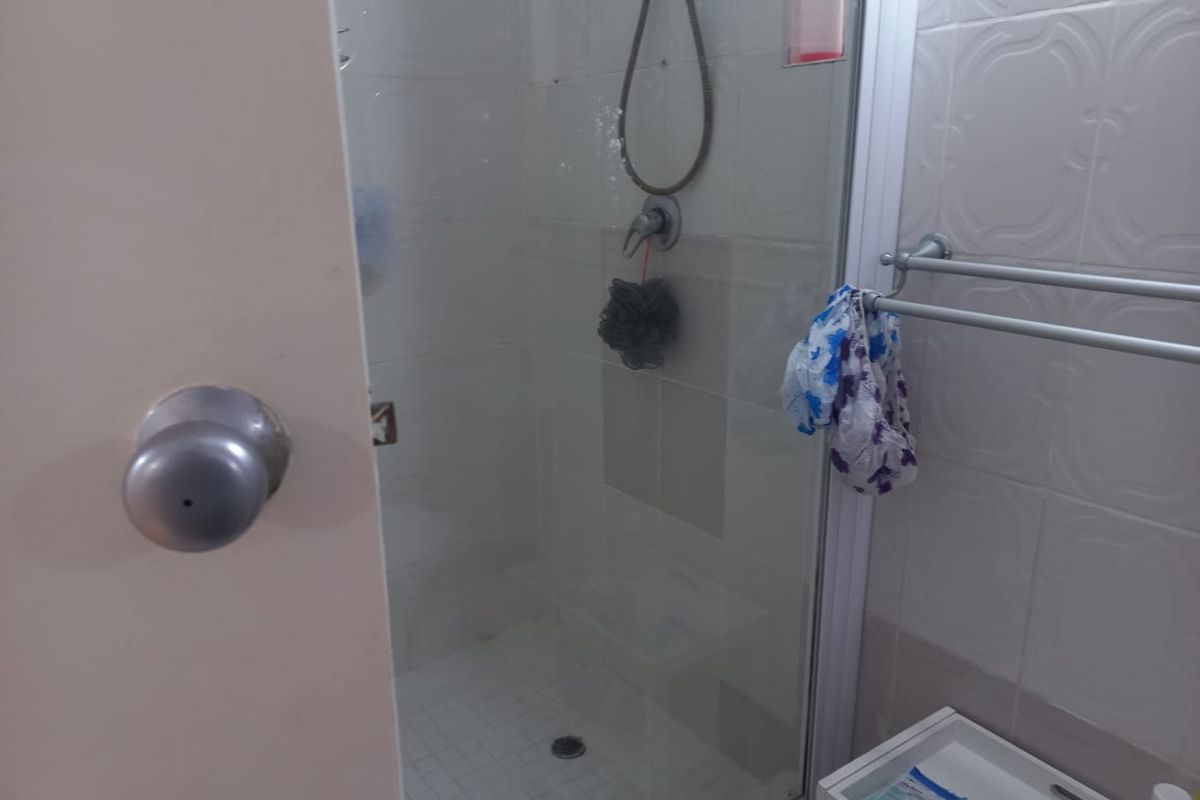 A functional bathroom shower enclosure featuring a glass door, tiled walls, and a wall-mounted towel rail.