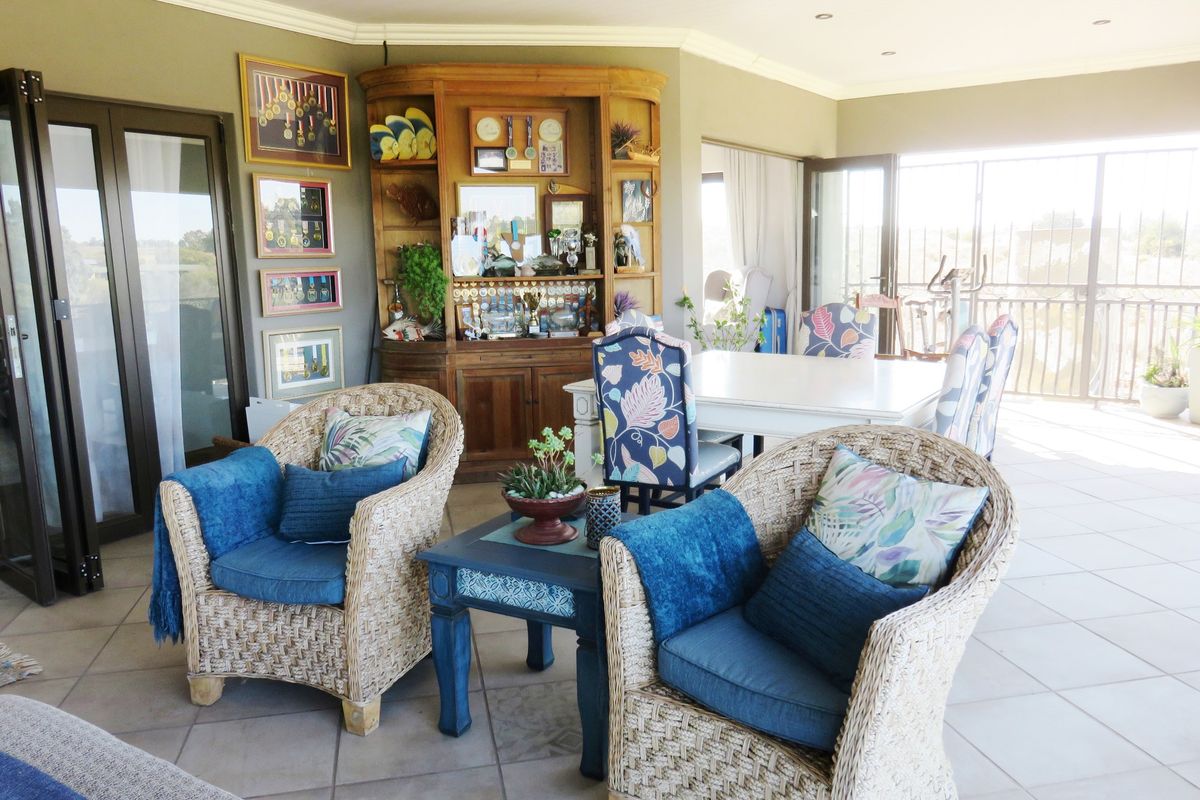 A spacious living area featuring tiled flooring, recessed lighting, and a built-in corner display cabinet, with access to an outdoor patio through bi-fold doors.