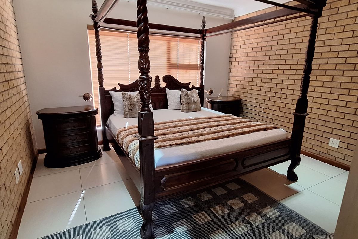 A bedroom featuring exposed brick walls, tiled flooring, and venetian blinds, providing a rustic yet functional living space.