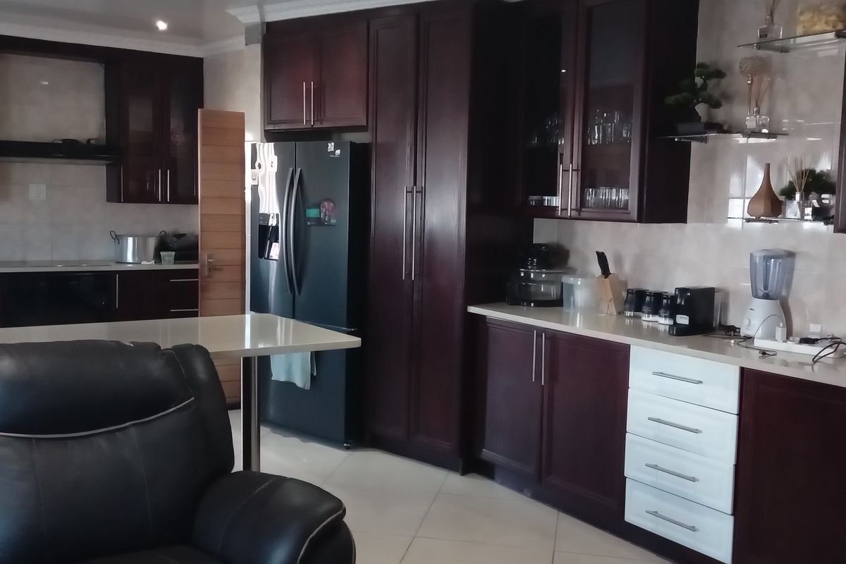 A spacious kitchen featuring dark wood cabinetry, stone countertops, integrated appliances, and a breakfast bar, offering a functional and well-maintained cooking space.