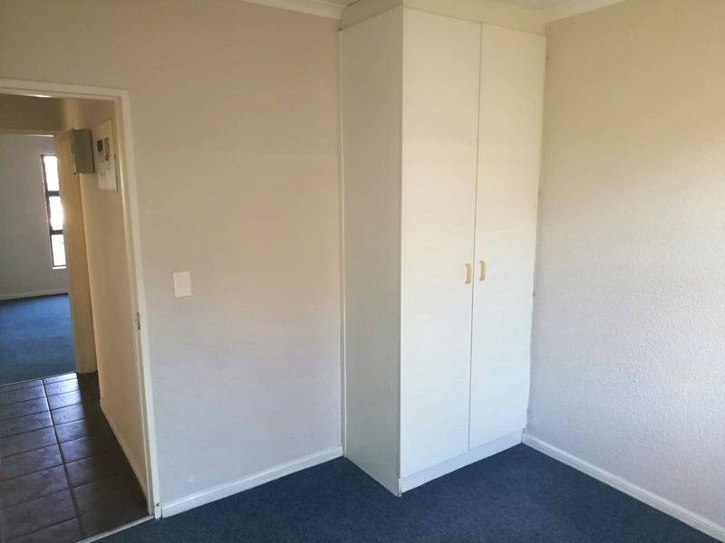 A simple, empty bedroom featuring a built-in cupboard and neutral wall finishes, providing a blank canvas for personalization.
