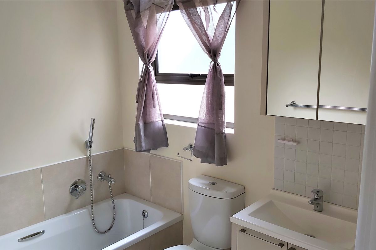 A functional bathroom featuring a bathtub with handheld shower, a vanity with basin, and a mirrored medicine cabinet.