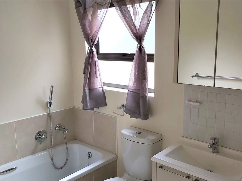 A functional bathroom featuring a bathtub with handheld shower, a vanity with basin, and a mirrored medicine cabinet.