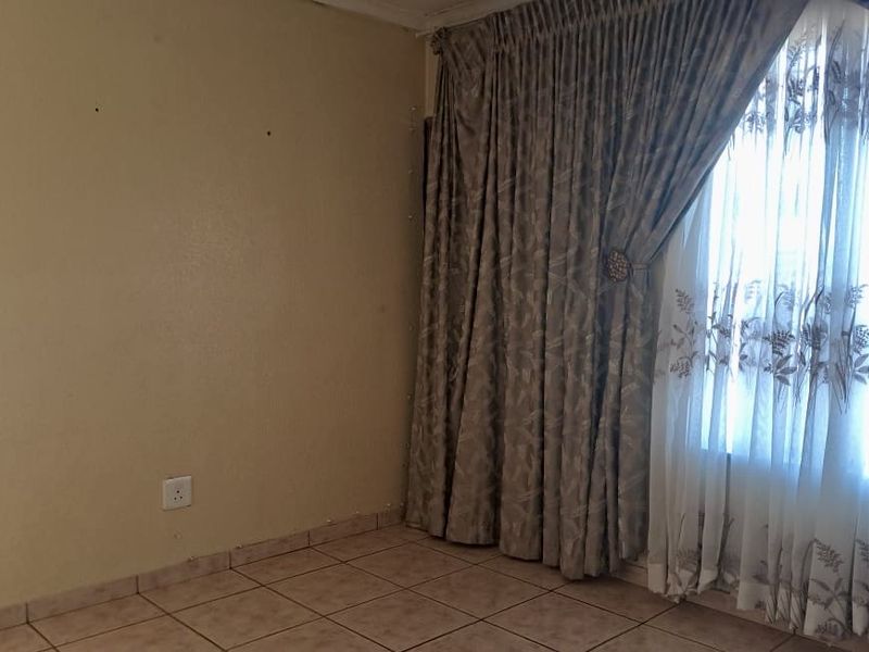 A vacant living room featuring neutral ceramic floor tiles and large window treatments, offering a blank canvas for interior design updates.