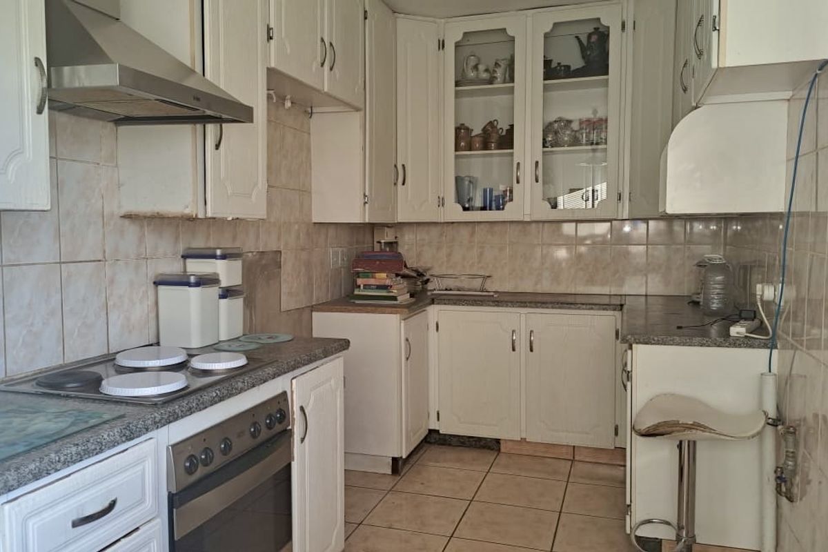 A dated kitchen featuring white cabinetry, tiled backsplash, and built-in appliances, offering potential for a modern renovation to enhance functionality and aesthetic appeal.