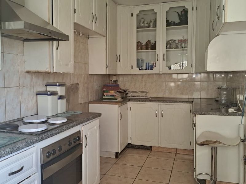 A dated kitchen featuring white cabinetry, tiled backsplash, and built-in appliances, offering potential for a modern renovation to enhance functionality and aesthetic appeal.
