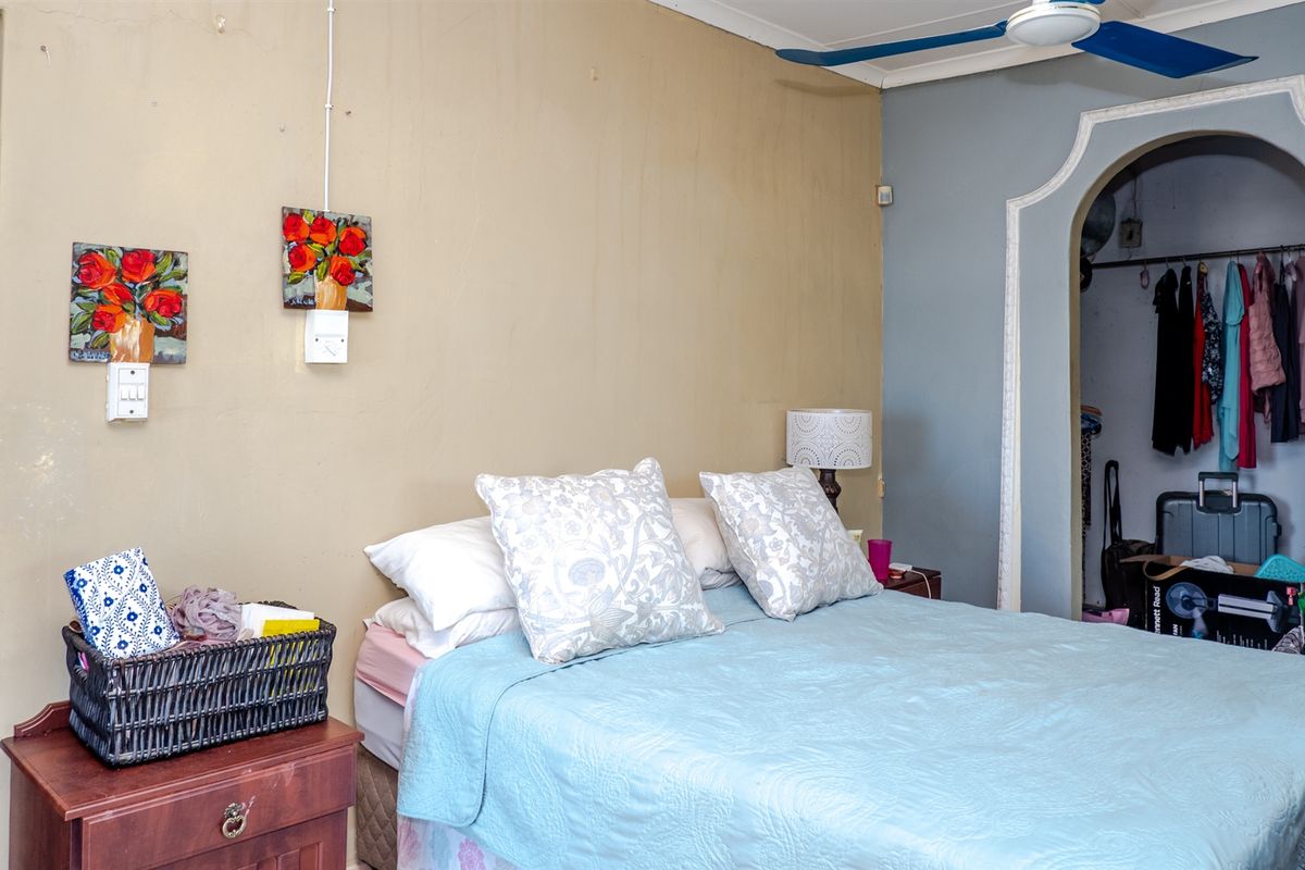 A bedroom featuring a ceiling fan and an arched entryway leading to a walk-in closet area with neutral wall tones.
