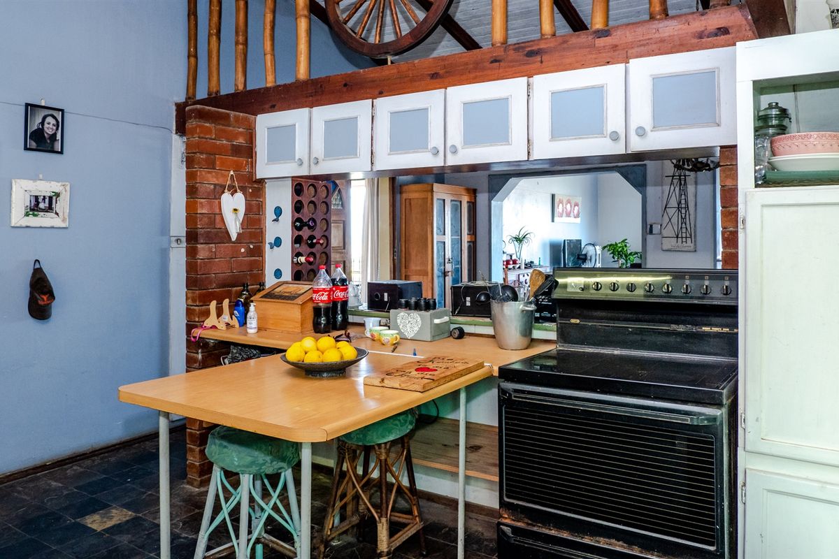 A rustic kitchen area featuring exposed brickwork, wooden cabinetry, a built-in stove, and a breakfast bar counter.