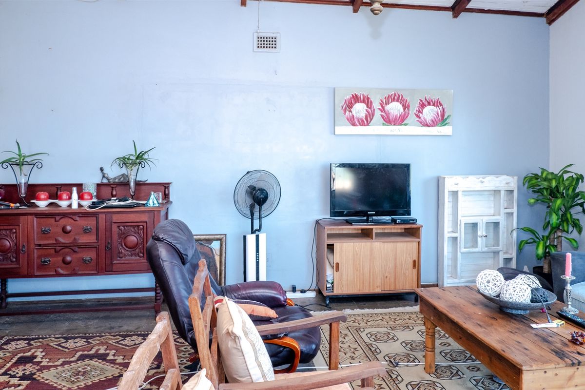 A living room featuring exposed stone wall detailing, timber ceiling beams, and a functional layout with neutral wall tones.
