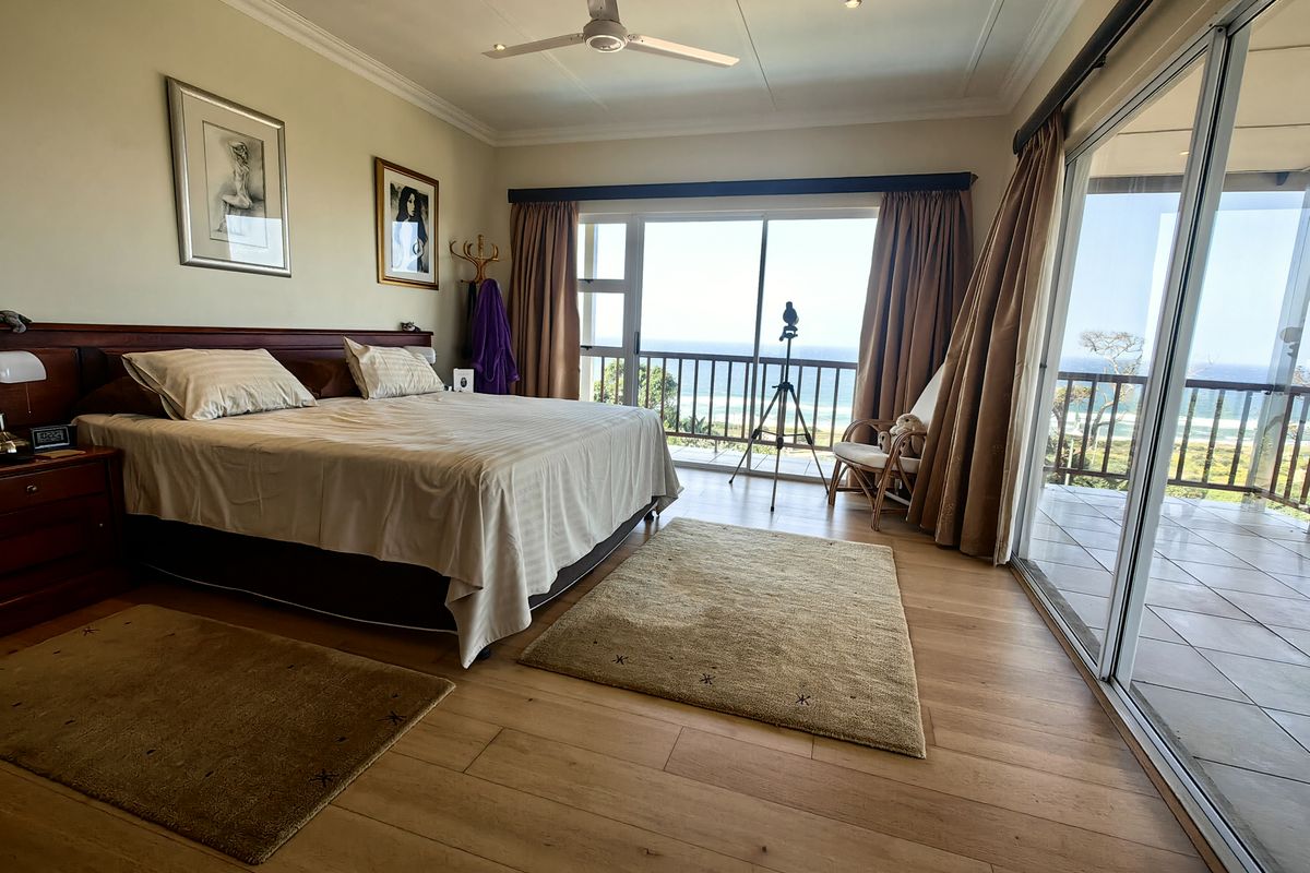 Spacious bedroom featuring laminate flooring, crown molding, and large sliding glass doors that open to a balcony with ocean views.