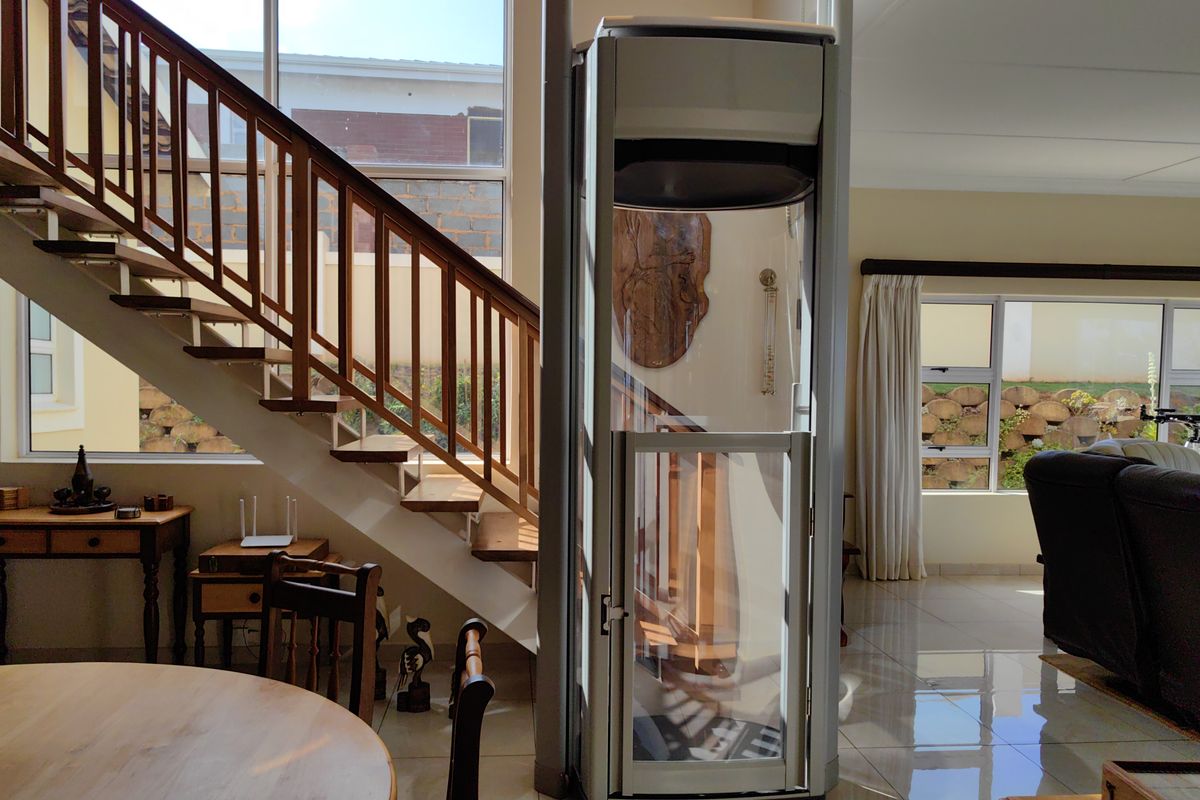 Spacious living area featuring a modern residential elevator and a timber staircase with large windows providing natural light.