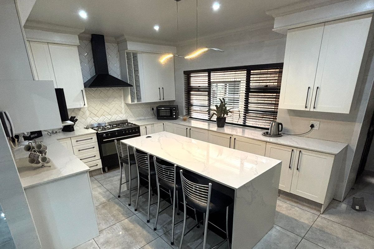 Modern kitchen featuring a central island with quartz countertops, gas stove, herringbone backsplash, and ample built-in cabinetry with recessed lighting.