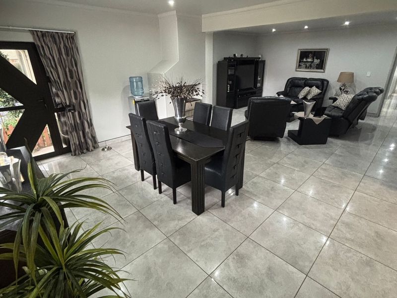 Spacious open-plan living and dining area featuring large format porcelain floor tiles, recessed downlighting, and a built-in fireplace.
