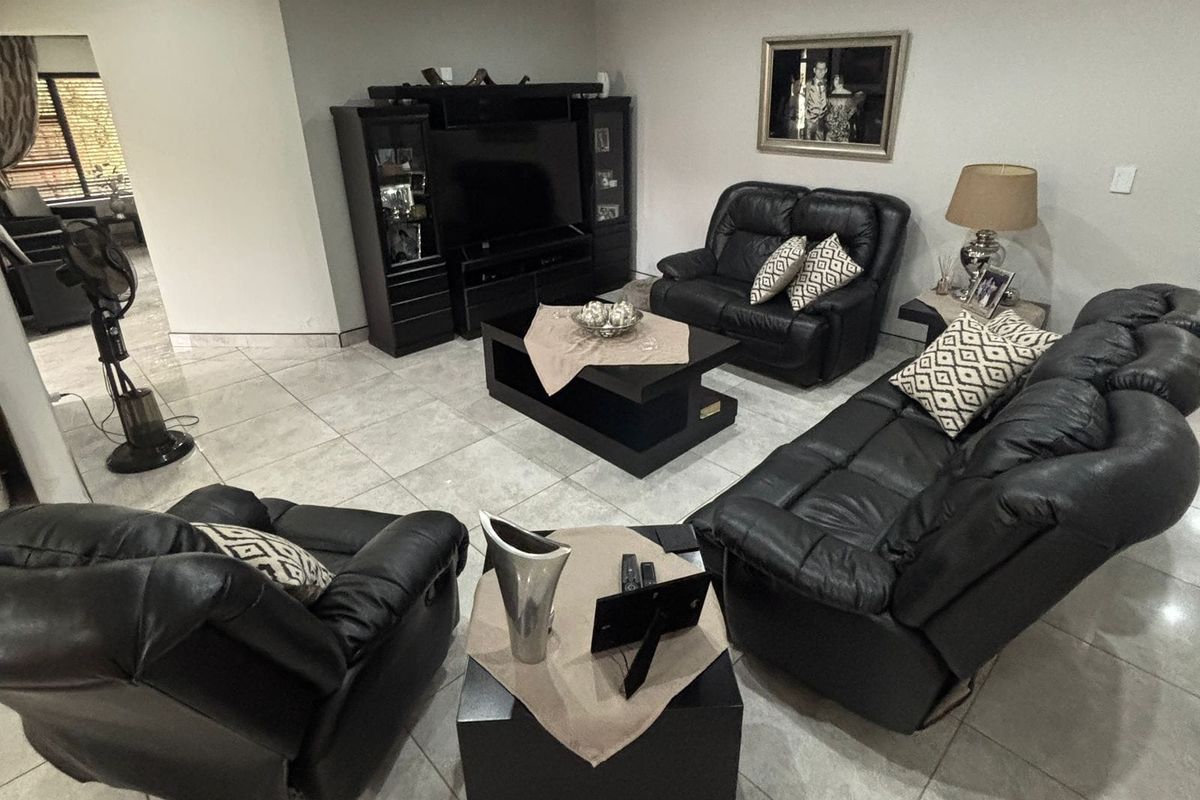 A spacious living room featuring neutral tiled flooring, recessed downlighting, and coved ceiling details, providing a comfortable and well-maintained area for relaxation.