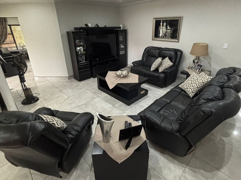 A spacious living room featuring neutral tiled flooring, recessed downlighting, and coved ceiling details, providing a comfortable and well-maintained area for relaxation.