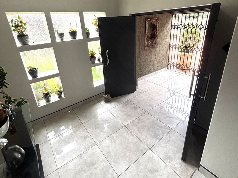 Bright entrance foyer featuring large format floor tiles, a textured feature wall, and unique recessed wall niches for display.