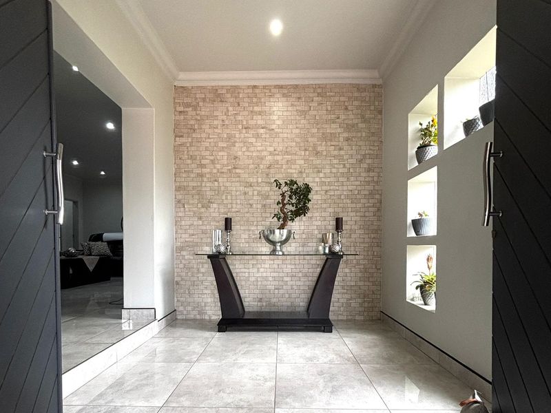 A modern entrance hall featuring a textured stone feature wall, tiled flooring, and built-in recessed wall niches for display.
