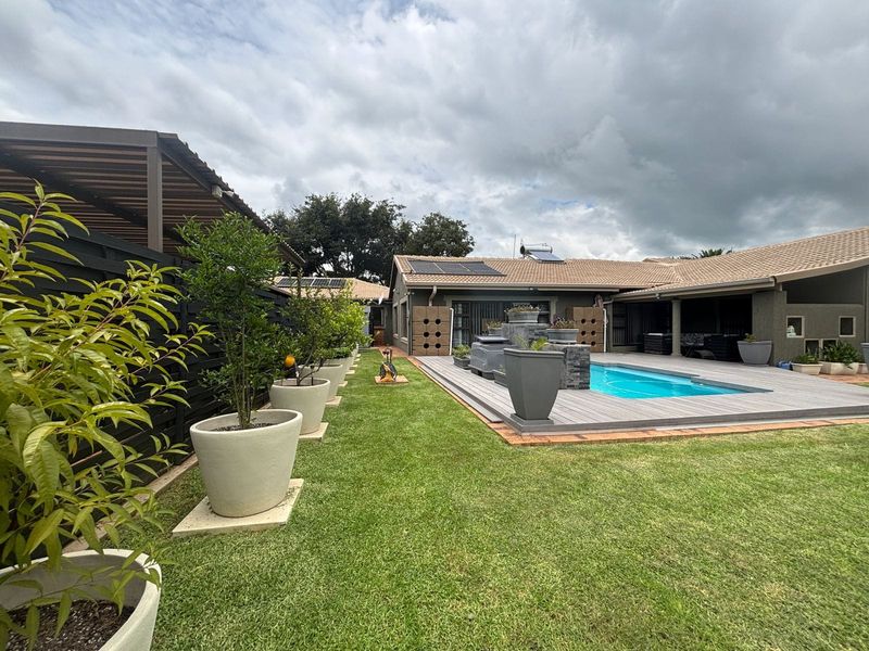 A well-maintained outdoor pool area featuring timber decking, a swimming pool, and solar water heating panels on the tiled roof.