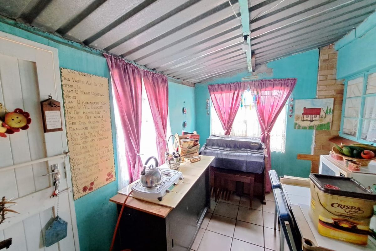 A rustic kitchen area featuring tiled floors, exposed brickwork, and a corrugated metal ceiling, requiring significant cosmetic updates and finish improvements.