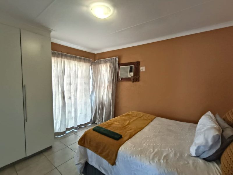 A bedroom featuring tiled flooring, a built-in wardrobe, and a window-mounted air conditioning unit.