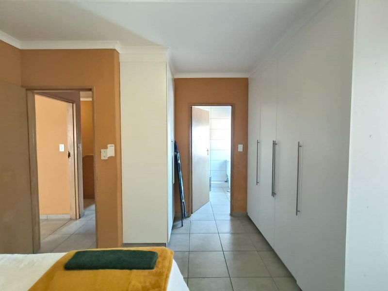 Bedroom featuring extensive built-in cupboard storage, tiled flooring, and direct access to an adjoining bathroom.