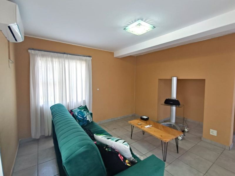 A living room featuring tiled flooring, a recessed wall niche, and an installed air conditioning unit.