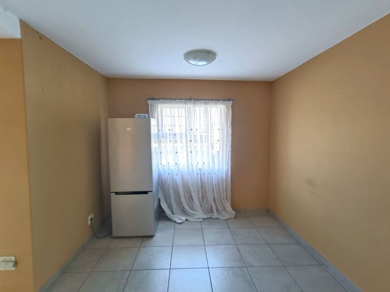 A vacant living area featuring neutral tiled flooring and plain painted walls, offering a blank canvas for interior design updates.