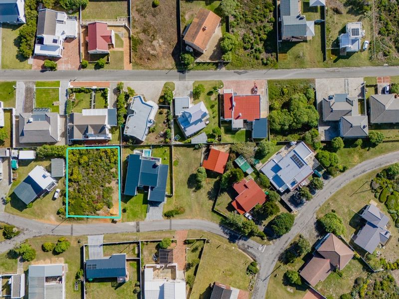 An aerial view of a vacant residential plot situated within an established coastal neighborhood, highlighting the available land and surrounding property context.