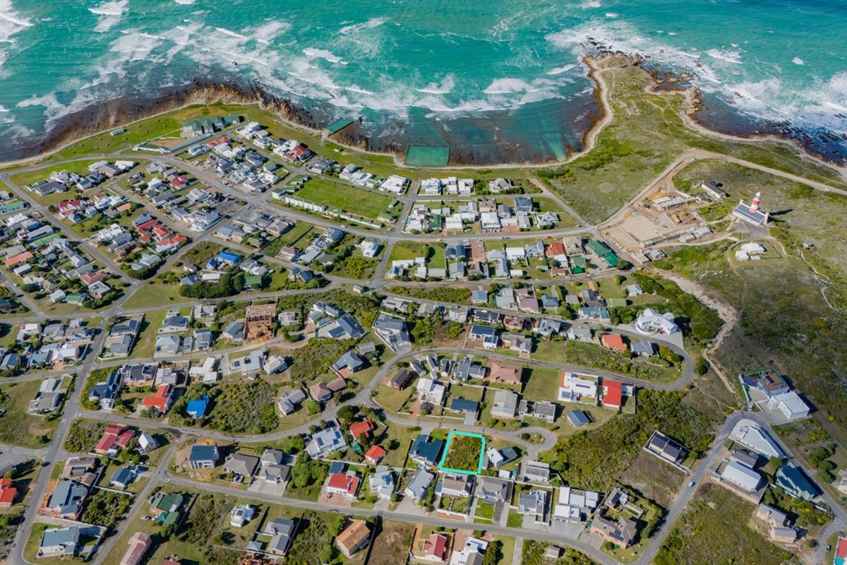 Aerial view of a vacant residential plot situated in a coastal neighborhood, highlighting its proximity to the ocean and local infrastructure.
