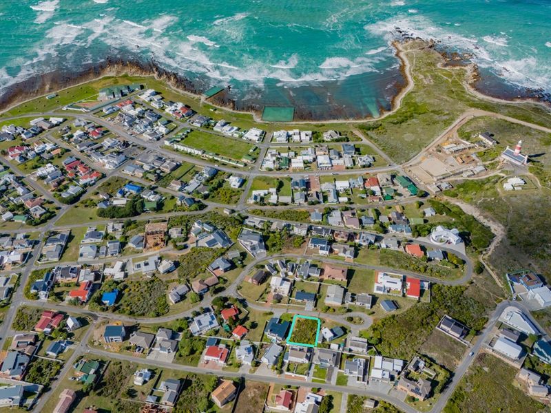 Aerial view of a vacant residential plot situated in a coastal neighborhood, highlighting its proximity to the ocean and local infrastructure.