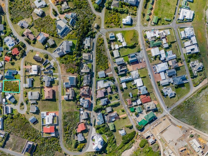 An aerial view of a vacant residential plot situated within an established coastal neighborhood, highlighting its location and surrounding infrastructure.