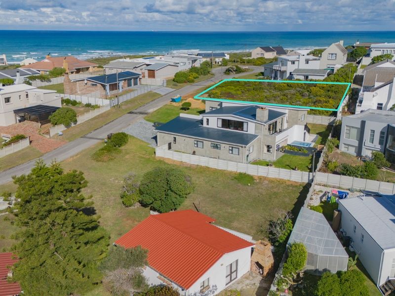 An aerial view of a vacant residential plot situated in a coastal neighborhood, highlighting its proximity to the ocean and surrounding residential properties.