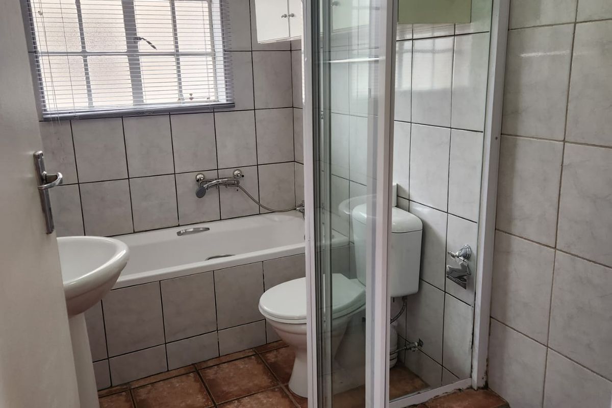 A functional bathroom featuring a bathtub, separate shower enclosure, pedestal basin, and toilet, finished with tiled walls and flooring.