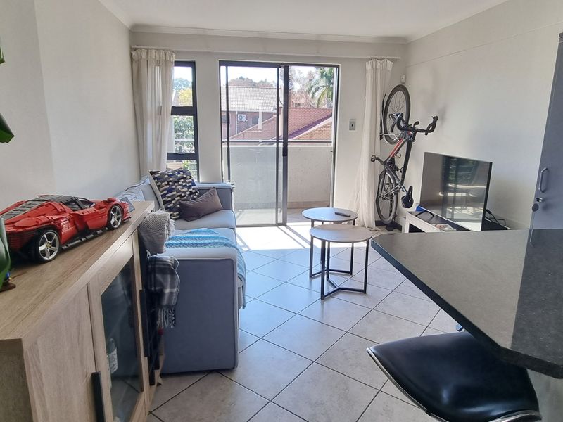 Open-plan living area featuring tiled flooring, a modern kitchen breakfast bar with granite countertops, and sliding door access to a private balcony.