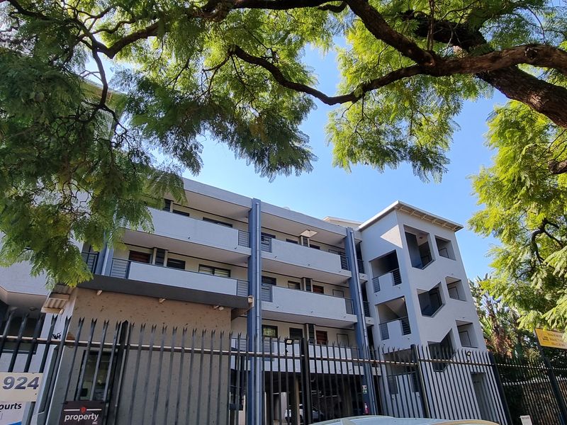 Exterior view of a multi-story apartment building featuring concrete balconies, external stairwells, and secure perimeter fencing.