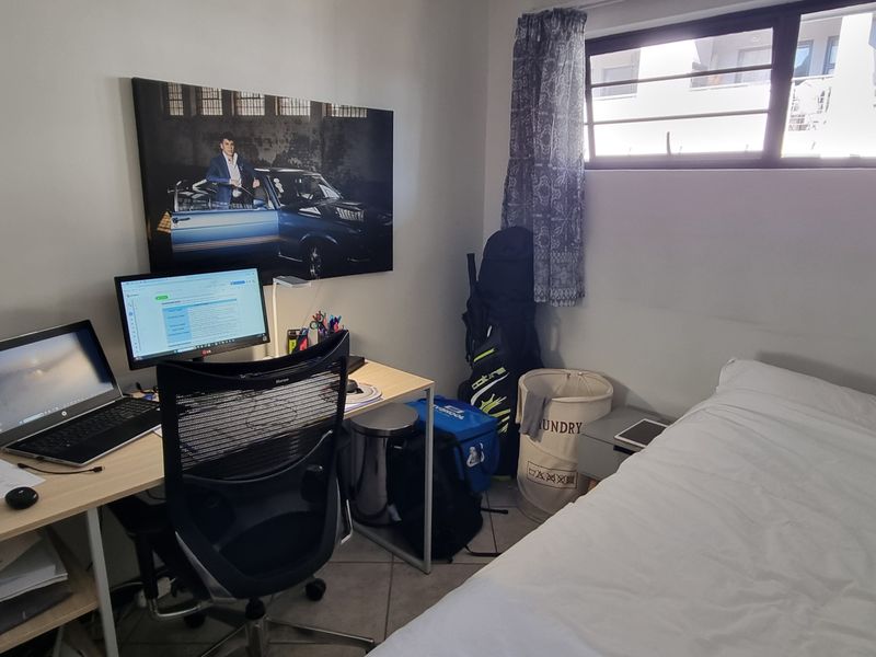 A functional bedroom featuring tiled flooring and a horizontal sliding window, providing natural light and a practical layout for a sleeping or study space.