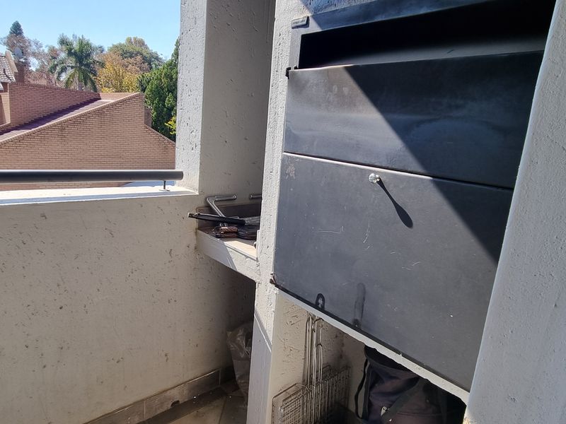 A balcony area featuring a built-in braai unit and metal railing, offering an outdoor space for grilling and relaxation.