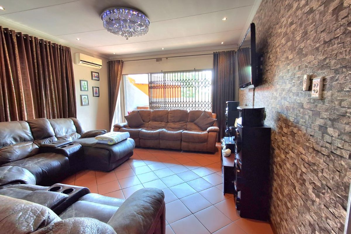 Spacious living room featuring tiled flooring, a stone-cladding feature wall, split-system air conditioning, and direct access to an outdoor area via sliding glass doors.