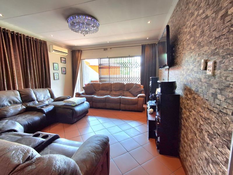 Spacious living room featuring tiled flooring, a stone-cladding feature wall, split-system air conditioning, and direct access to an outdoor area via sliding glass doors.