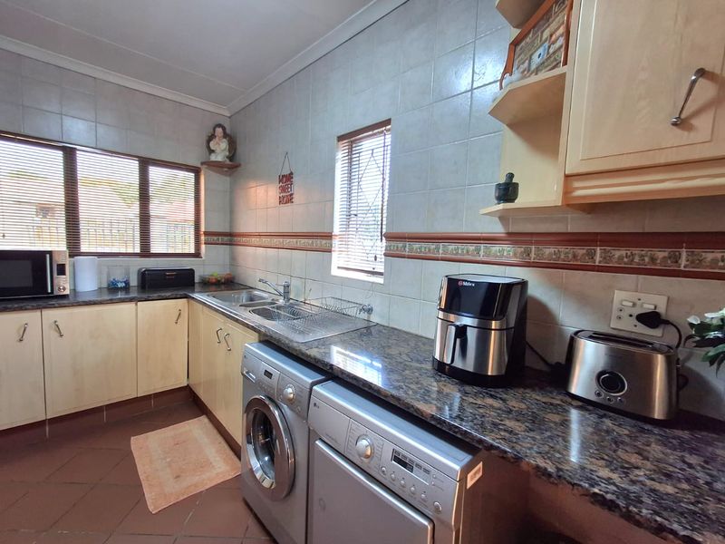 A functional kitchen featuring granite countertops, laminate cabinetry, tiled backsplash, and integrated laundry appliance connections.