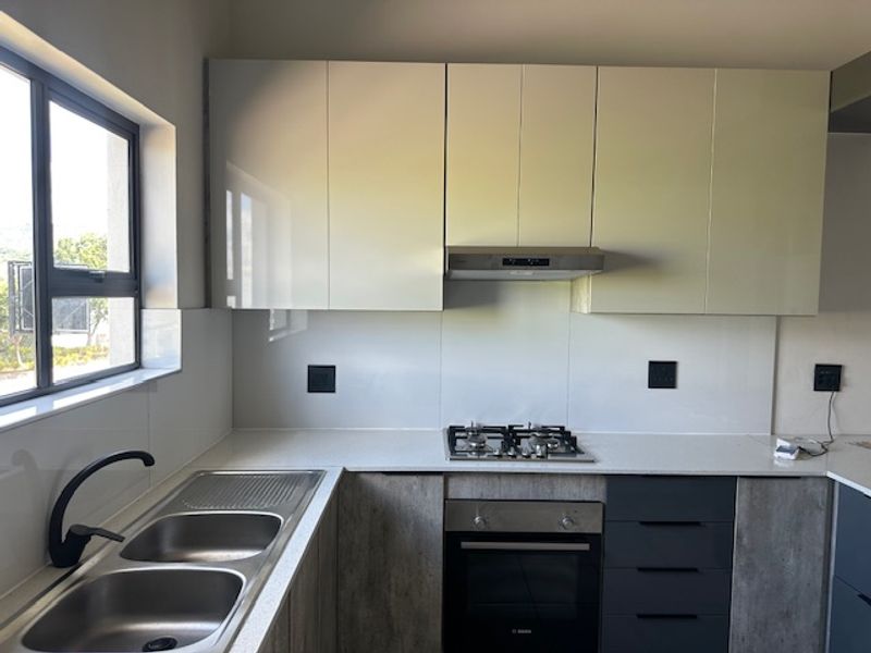 Modern kitchen featuring sleek laminate cabinetry, quartz countertops, a gas hob, built-in oven, extractor fan, and a double bowl stainless steel sink.