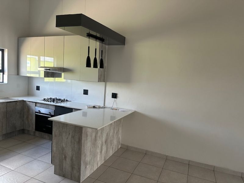 Modern kitchen featuring sleek cabinetry, stone countertops, integrated gas hob, oven, and stylish pendant lighting, offering a clean and functional culinary space.
