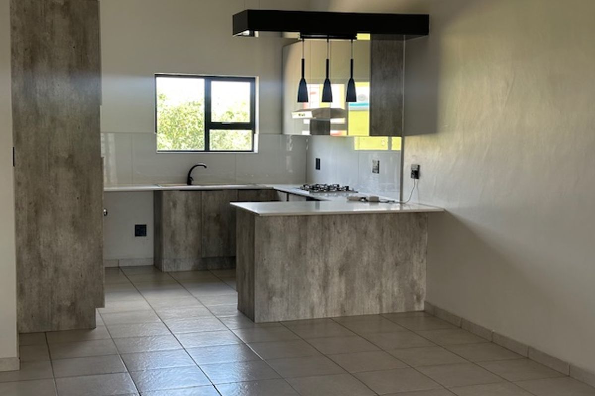 Modern kitchen featuring textured cabinetry, stone countertops, a gas hob with extractor, and tiled flooring in an open-plan layout.