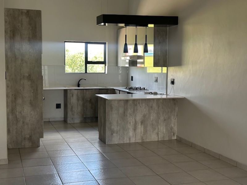 Modern kitchen featuring textured cabinetry, stone countertops, a gas hob with extractor, and tiled flooring in an open-plan layout.