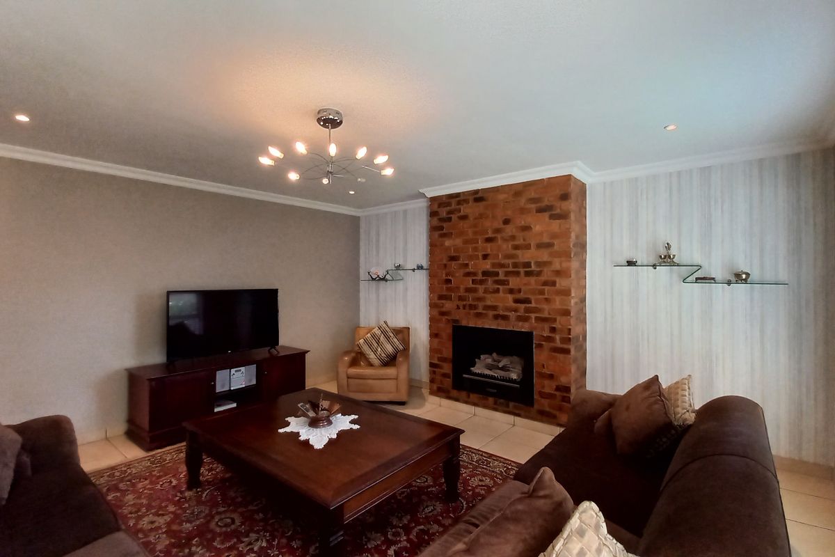 A comfortable living room featuring an exposed brick fireplace, tiled flooring, and modern lighting, creating a warm and inviting atmosphere.
