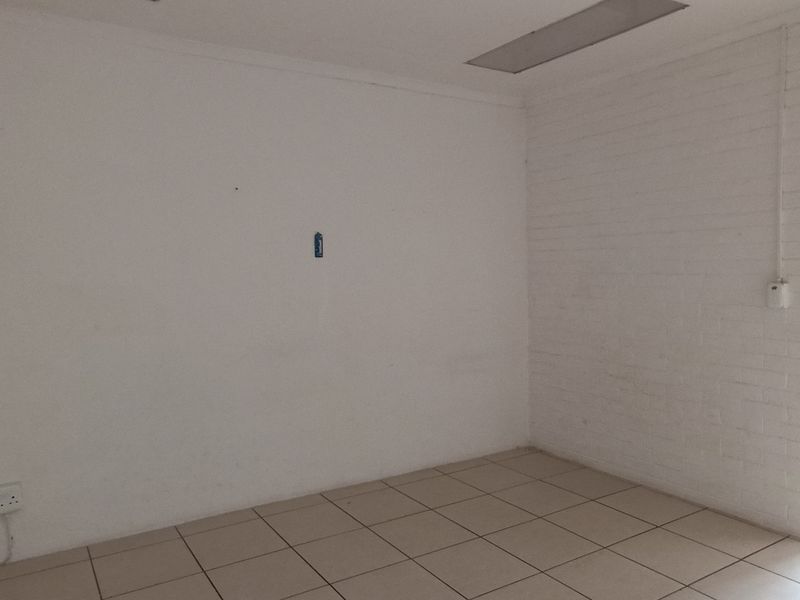 An empty bedroom featuring tiled flooring, an exposed brick wall, and recessed ceiling lighting, ready for a fresh update.