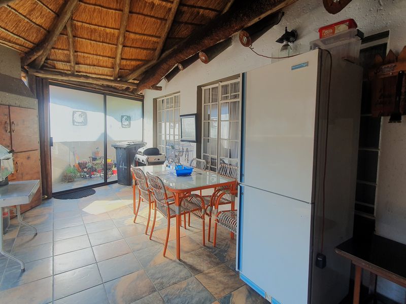 Covered patio area featuring a traditional thatched roof, exposed timber beams, and tiled flooring, providing a rustic outdoor entertainment space.