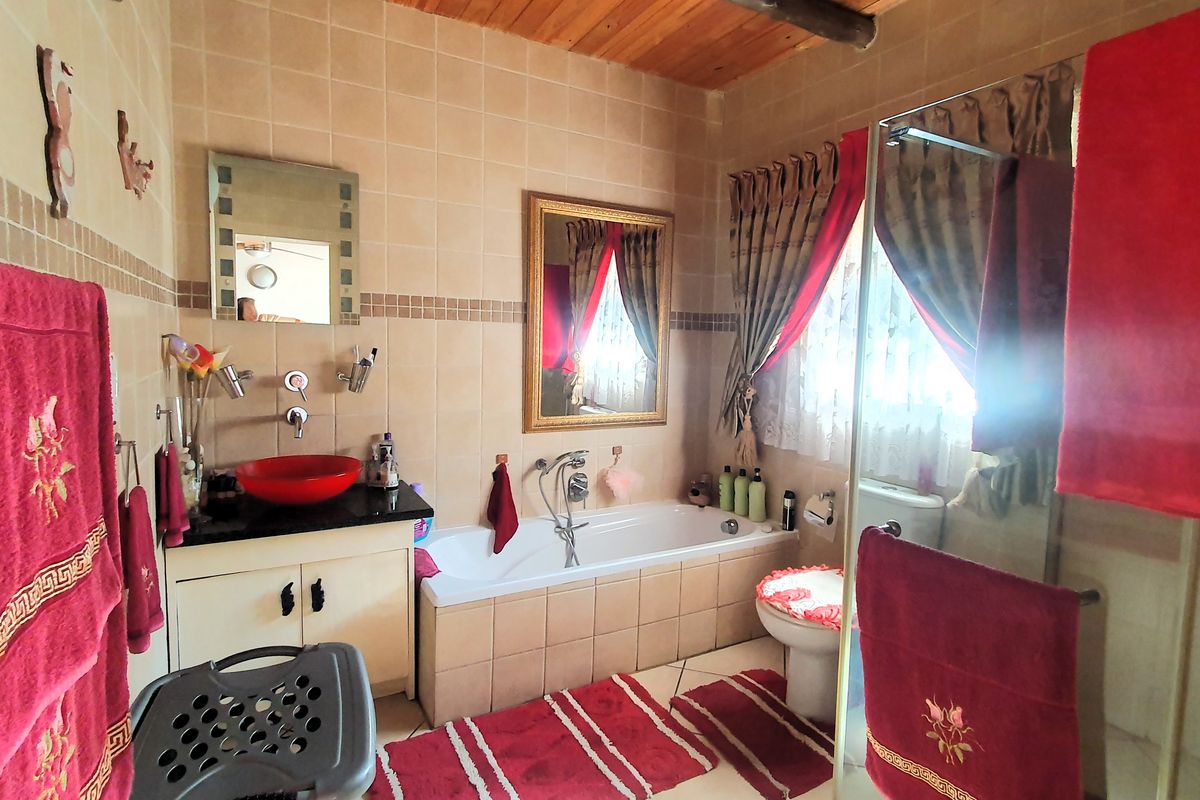 A functional bathroom featuring a built-in vanity, drop-in bathtub, separate shower enclosure, and tiled wall finishes with a timber ceiling.
